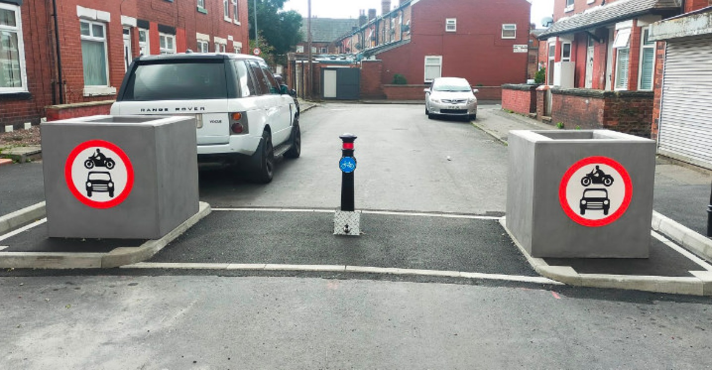 A filter on a residential street with two cars parked behind.
